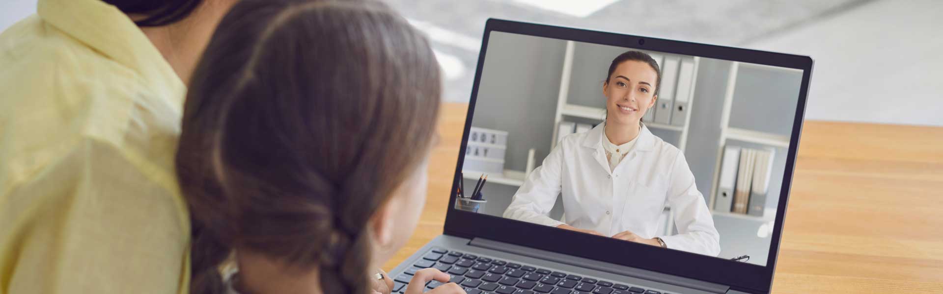 Telemedicine - mother and daughter speaking to doctor on a laptop