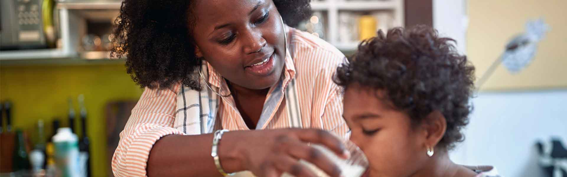 Mother helping daughter to drink