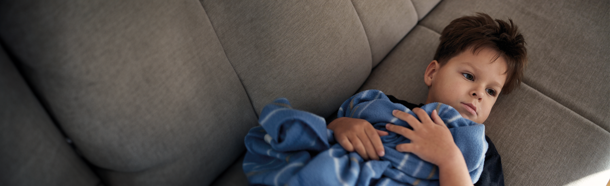 boy sat on sofa with blanket