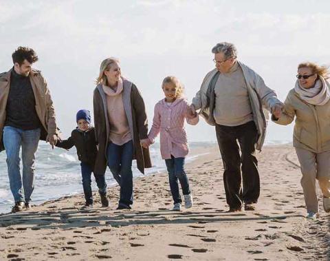 Een gezin loopt hand in hand over het strand.