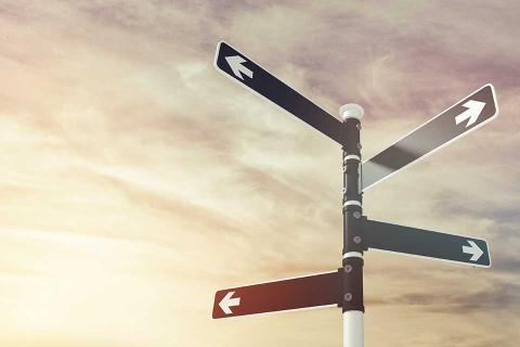 Black signpost with white arrows pointing in different directions