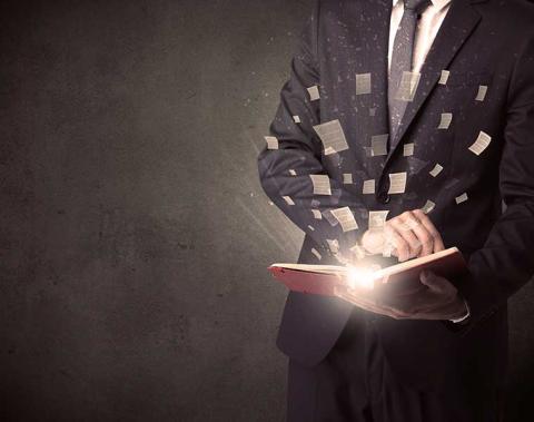 Man opening a book with light spilling out of it