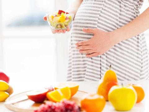 Pregnant woman holding a bowl of fruit