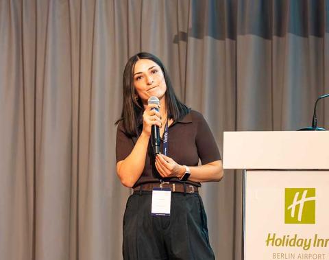 Dr. Fatma Ilgaz holding a microphone and speaking