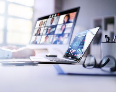 Person in an online meeting on one screen with a laptop open