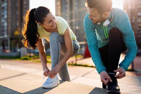 Two young people wearing sports clothes tying shoe laces